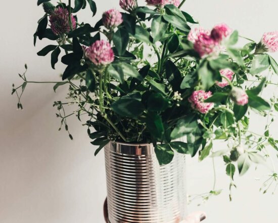 Hand hält Topf mit Wildblumen